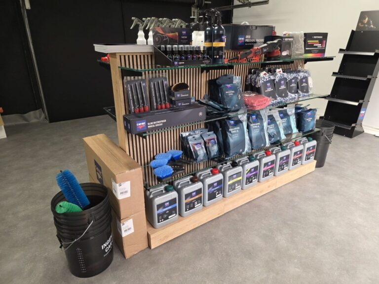 Pr&eacute;sentoir Cartec en bois &agrave; &eacute;tag&egrave;res vitr&eacute;es, avec microfibres, brosses, seaux et produits d&rsquo;entretien, vue de trois quarts