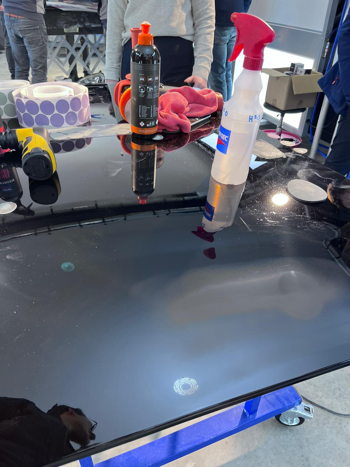 Polisseuse et matériel sur un panneau noir avant une démonstration Cartec à Amsterdam