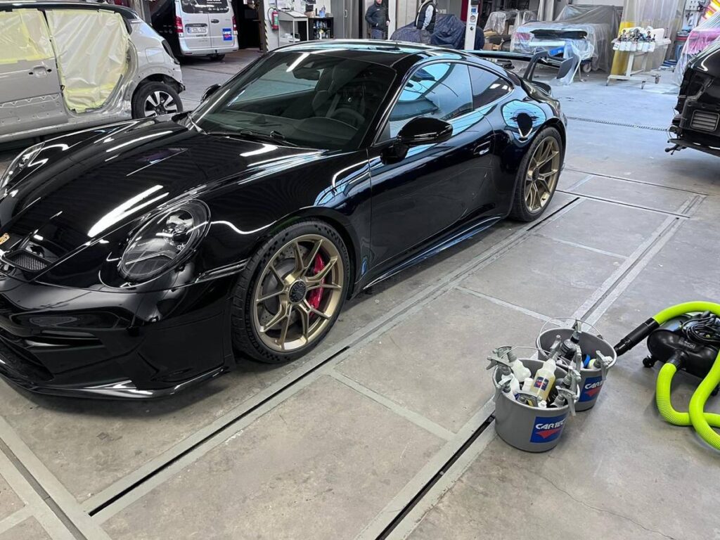 Porsche 911 noire dans l&rsquo;atelier du client, pr&ecirc;te pour la d&eacute;monstration de detailing