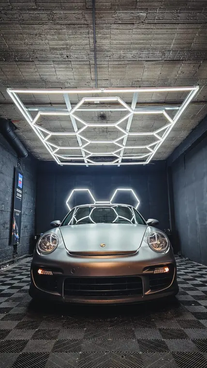 Porsche 911 claire sous &eacute;clairage d&rsquo;atelier hexagonal