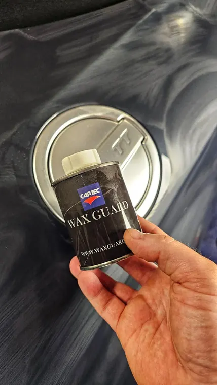 Bo&icirc;te Cartec Wax Guard tenue devant une carrosserie