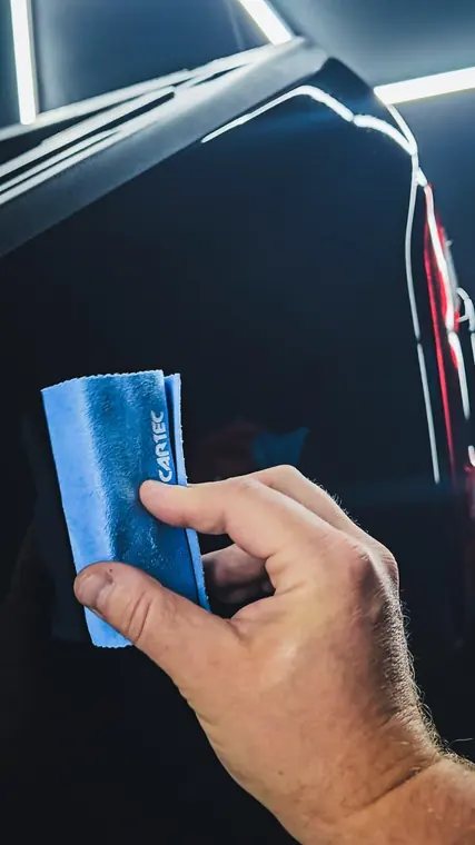 Main avec microfibre dans un habitacle automobile
