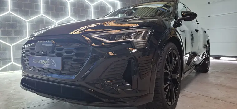 Audi noire devant une paroi lumineuse hexagonale