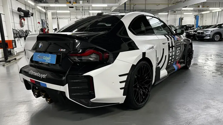 BMW M2 &agrave; livr&eacute;e noire et blanche dans un atelier