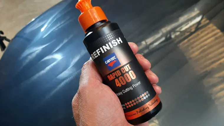 Flacon Cartec Refinish tenu devant une carrosserie