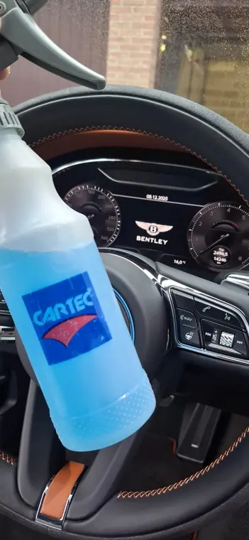 Spray d&rsquo;entretien tenu pr&egrave;s d&rsquo;un volant automobile