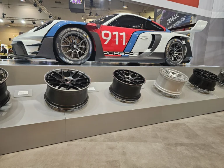 Voiture et jantes exposées sur un stand à Essen Motor Show 2025