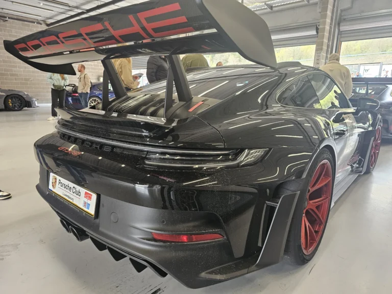 Porsche noire &agrave; grand aileron sous un stand &mdash; Porsche Days 2026