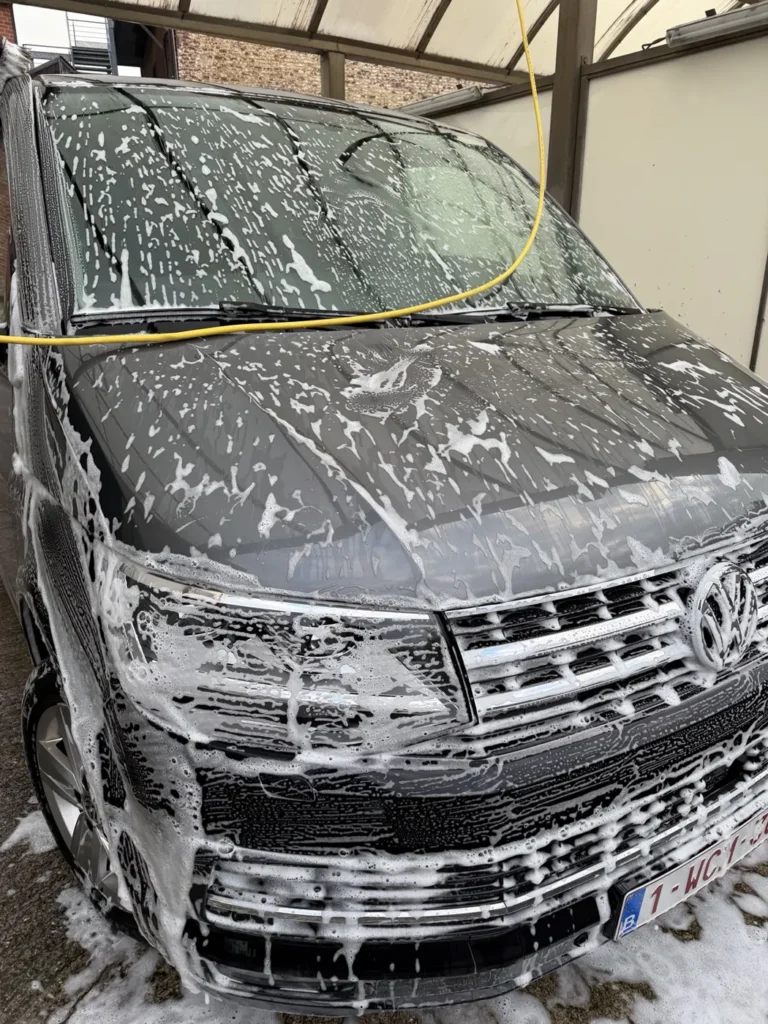 Vue avant d&rsquo;un Volkswagen noir couvert de mousse dans une station de lavage