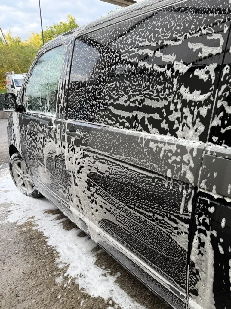 Flanc d&rsquo;un Volkswagen noir couvert de mousse pendant une d&eacute;monstration de lavage Royal Care