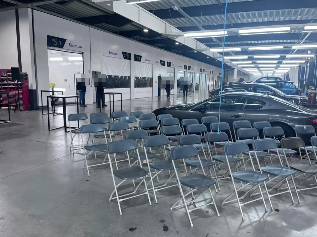 Chaises install&eacute;es dans l&rsquo;atelier pour l&rsquo;inauguration et la d&eacute;monstration Cartec, v&eacute;hicules expos&eacute;s &agrave; droite