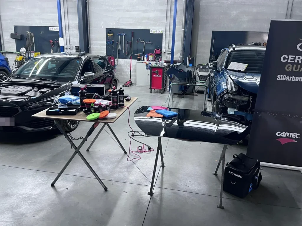 Table de d&eacute;monstration Cartec Refinish avec pads, microfibres et panneau de carrosserie dans l&rsquo;atelier