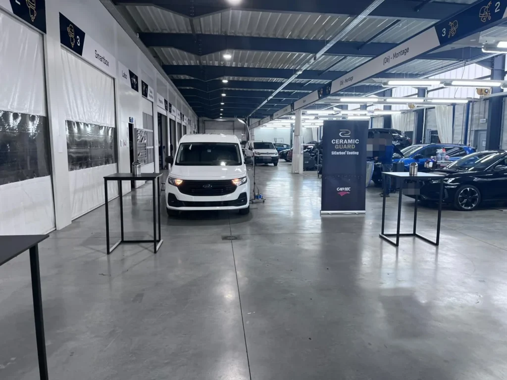 Vue de l&rsquo;atelier avec utilitaire Ford blanc, banni&egrave;re Ceramic Guard et v&eacute;hicules expos&eacute;s